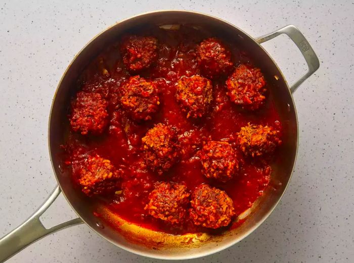 The meatballs simmering in a tomato broth until the rice is perfectly cooked.