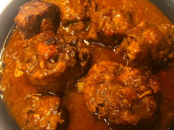 A close-up view of oxtails served with rich gravy.