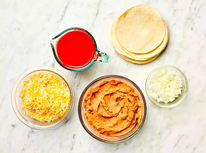 Refried Bean and Cheese Enchiladas Ingredients on a Marble Countertop