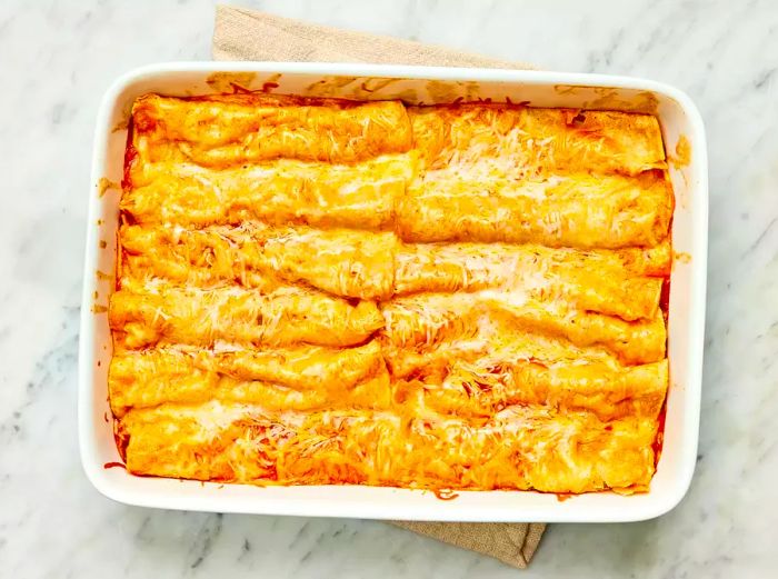 Baked Refried Bean and Cheese Enchiladas in a white casserole dish