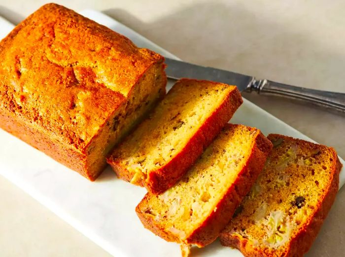 A loaf of banana bread sliced on a marble countertop.