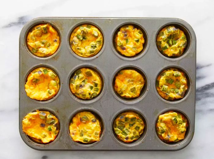 A top-down view of the freshly baked frittatas in a muffin tin.