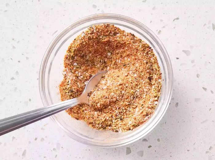 Spice blend in a glass bowl with a spoon