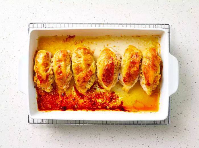 A baking dish containing six roasted stuffed chicken breasts