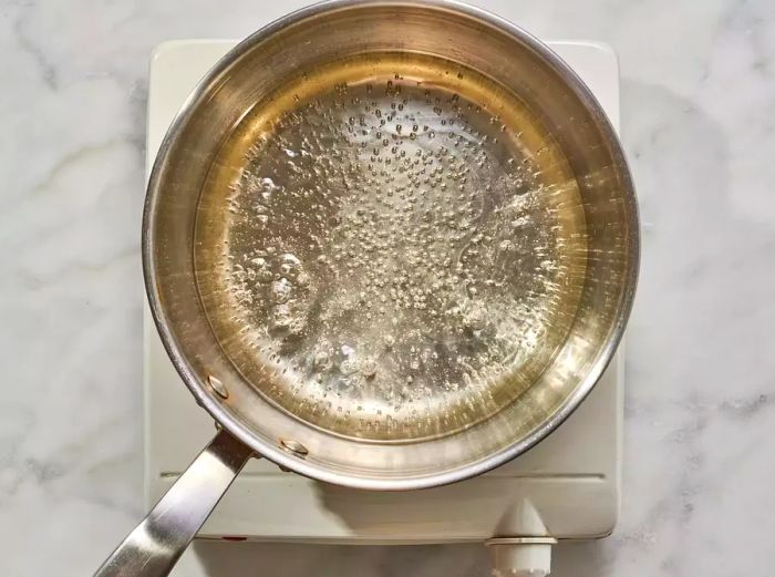 A simmering pan with water, sugar, salt, and oil