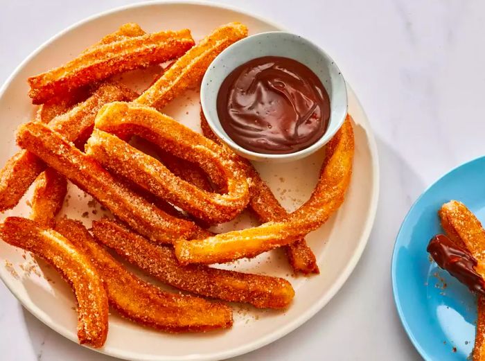 A plate of churros served alongside a rich chocolate dipping sauce.