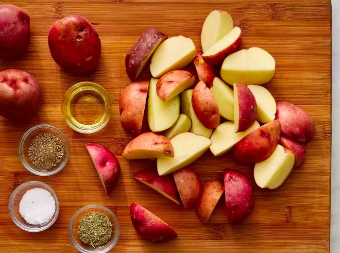 Chop the potatoes on a cutting board, keeping the oil, salt, and spices nearby for easy access.