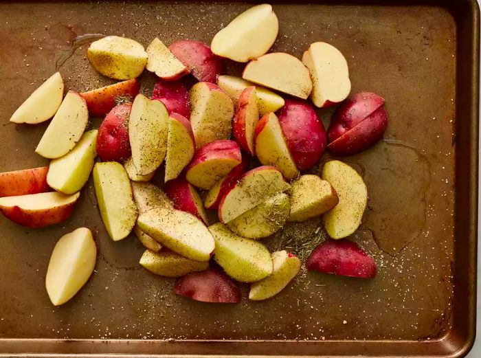 Cut the seasoned potatoes, which are coated in oil, and arrange them on a baking sheet.