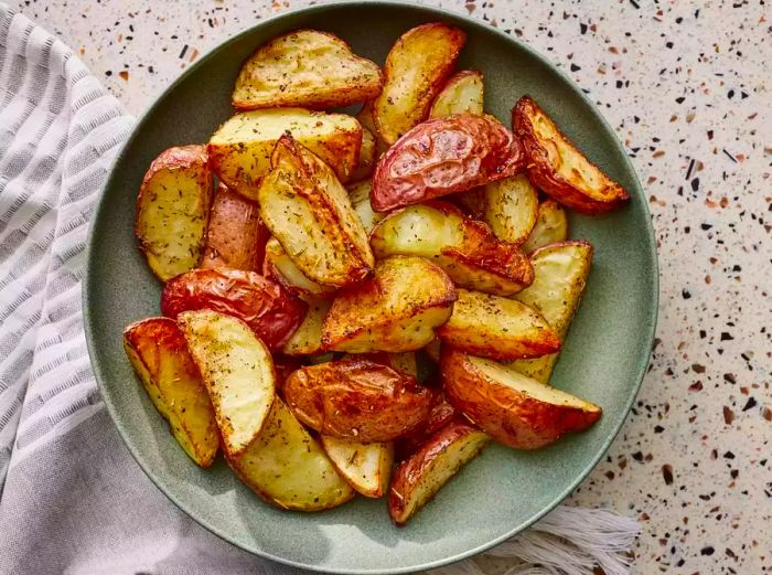 A top-down view of a plate filled with crispy, golden-brown roasted potatoes.