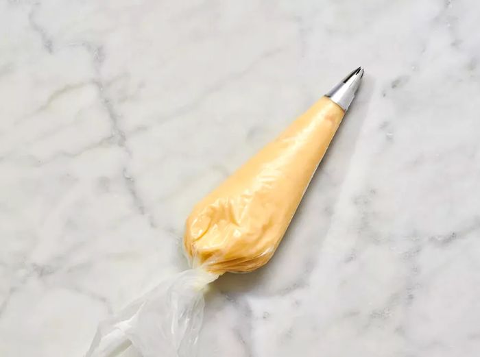 A pastry bag filled with dough, equipped with a large star tip.