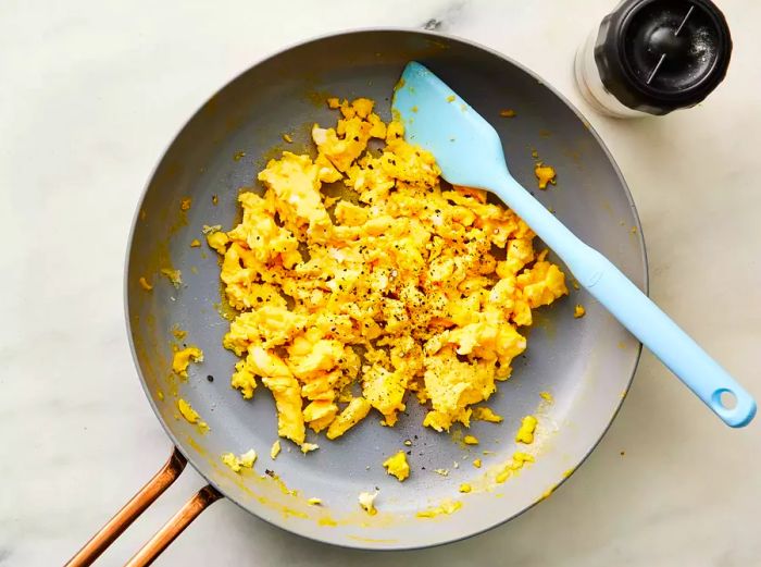 scrambled eggs and blue spatula in a skillet