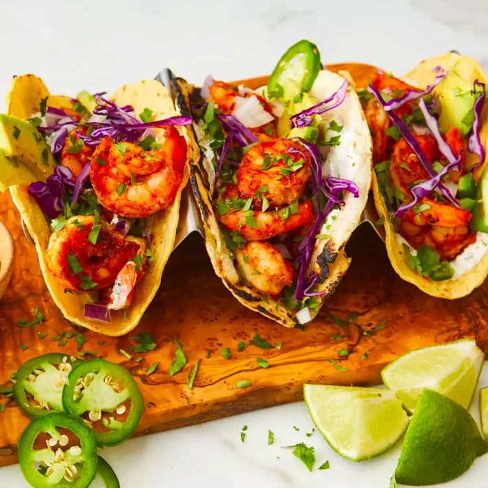 close-up shot of three shrimp tacos topped with cilantro lime crema at a taco stand