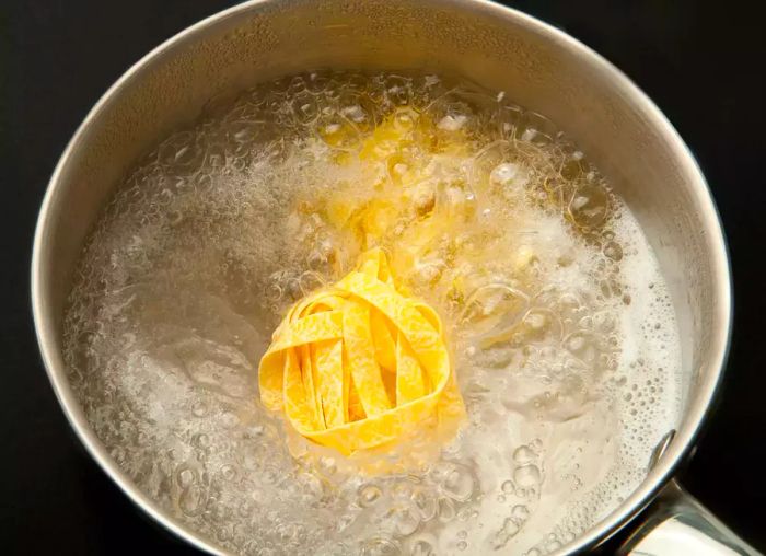 A pot of pasta noodles cooking in starchy water