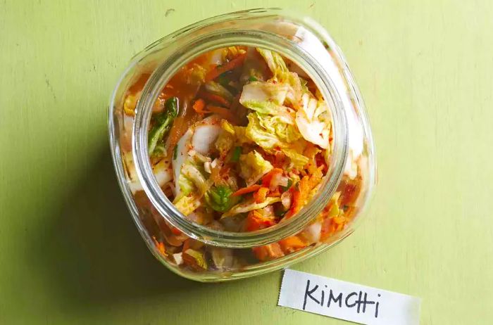 Kimchi in a jar, set against a green backdrop