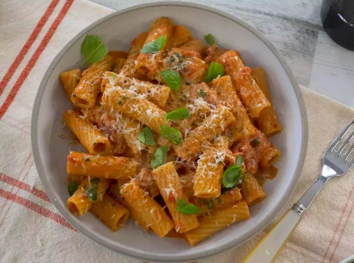 A close-up of a bowl of pasta alla vodka, garnished with fresh basil.