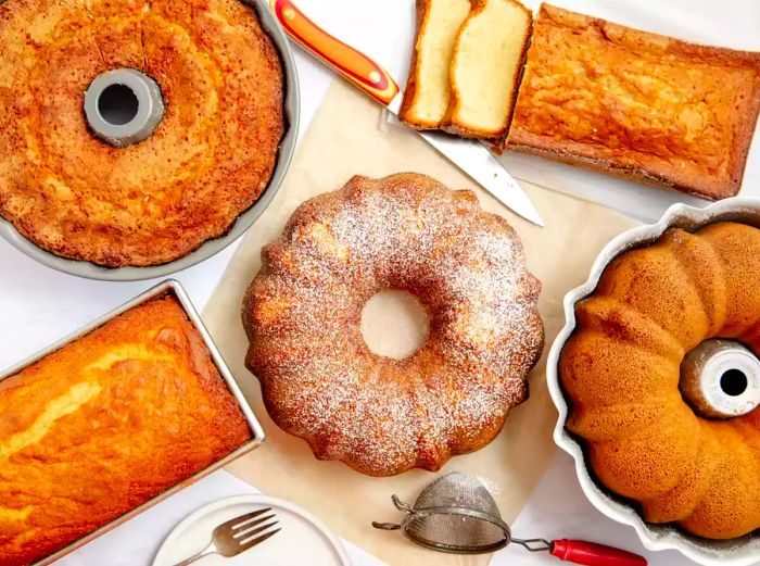 Five different pound cakes displayed on a white countertop.