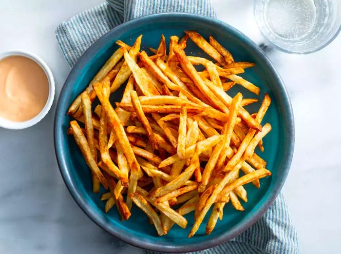 Overhead view of a plate of crispy air fryer French fries with dipping sauce on the side