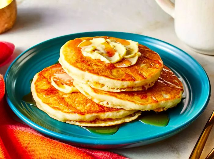 a stack of three flawless pancakes on a deep teal plate