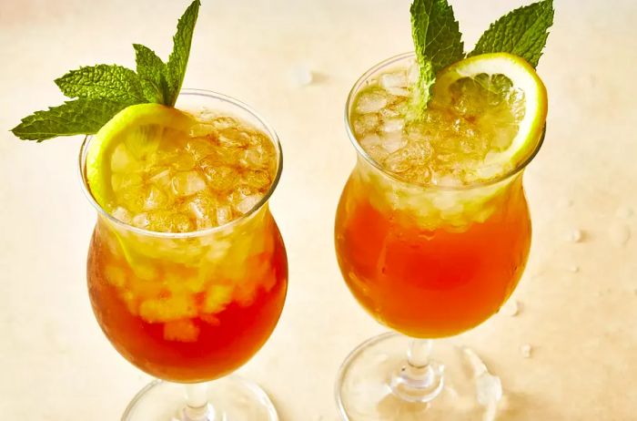 Two refreshing Long Island Iced Teas, served in tall glasses and garnished with mint and fresh lemon.