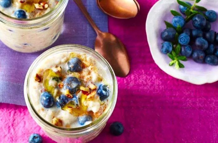 Oatmeal jars topped with a vibrant mix of fresh blueberries, crunchy nuts, and a drizzle of honey.