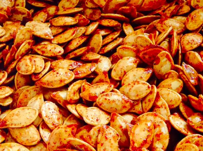 A close-up shot of a pile of Spiced Maple Pumpkin Seeds, looking warm and delicious.