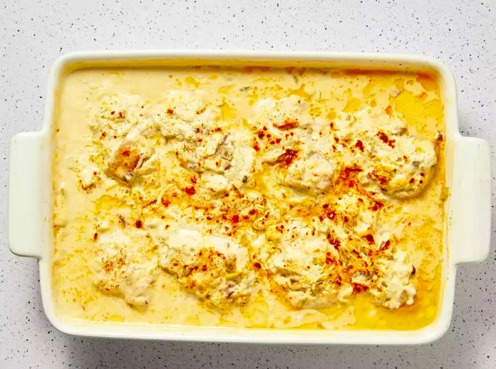 A baking dish filled with bacon-wrapped chicken breasts and dried beef smothered in a creamy sauce.