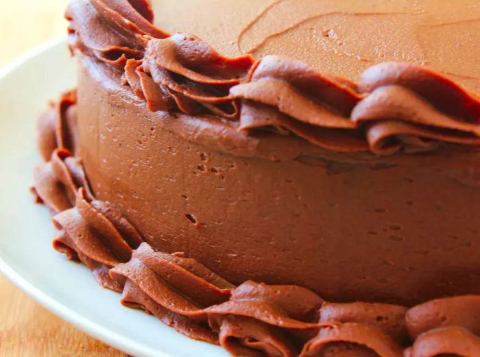 Side view of a chocolate-layer cake frosted with chocolate and piped with a decorative border.