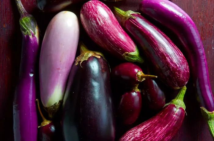 A variety of eggplants laid out on a wooden table.