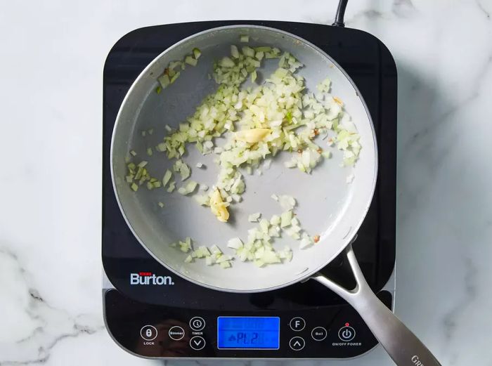 Onion and garlic added to the pan, cooking until fragrant and tender.