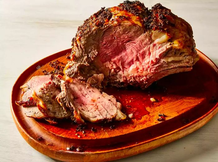 A close-up of a cutting board with a garlic-infused prime rib resting, a few slices ready to be served.