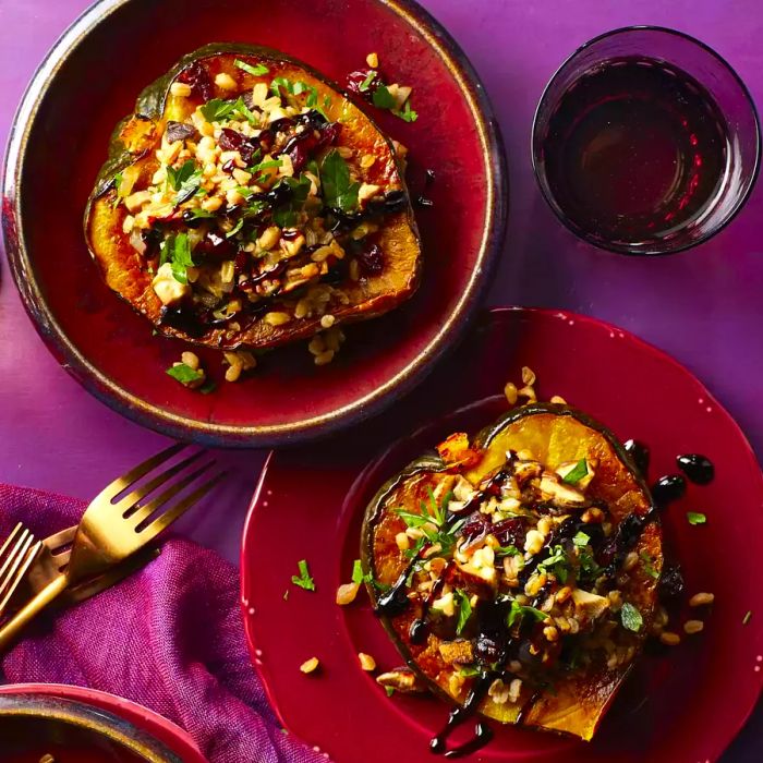 Two plates of roasted acorn squash halves stuffed with farro