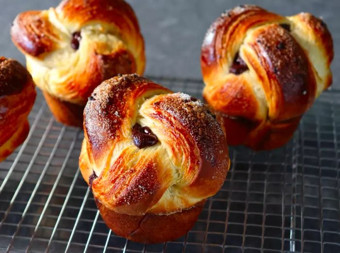 Close-up view of soft brioche buns with chocolate peeking out from their braided tops.