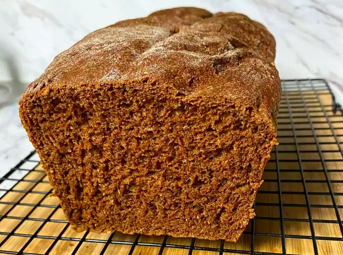 Close-up of a loaf of Bread Machine Pumpernickel Bread cooling on a rack.