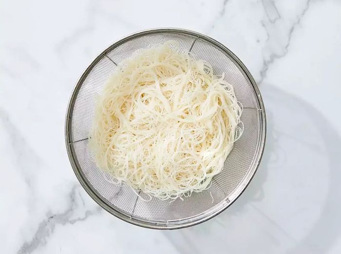 rice noodles draining after being soaked in warm water