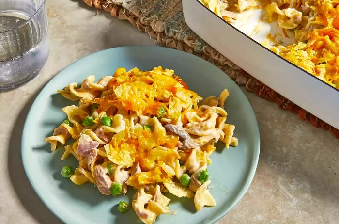 A top-down view of a plate of the ultimate tuna noodle casserole with the casserole dish placed nearby.