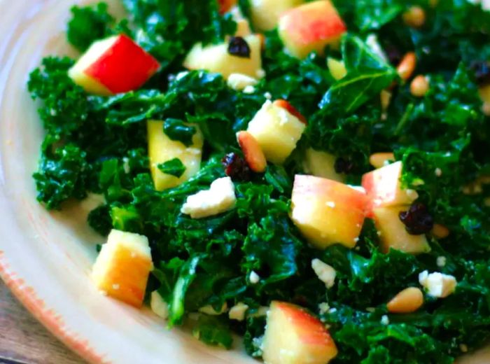 close-up of a salad with lacinato kale, diced apples, toasted pine nuts, and feta cheese