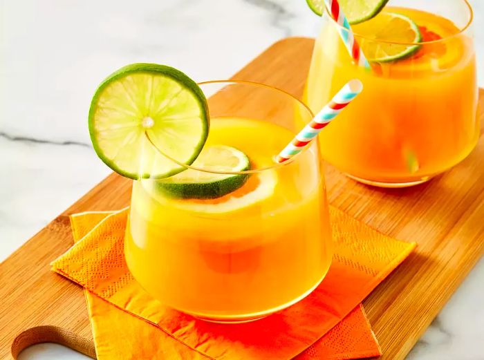 A high-angle shot of two glasses of Jamaican rum punch, garnished with lime slices and colorful straws.