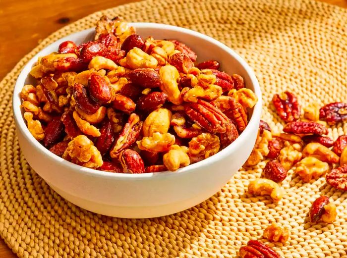 A bowl of sweet, salty, and spicy party nuts placed on a placemat