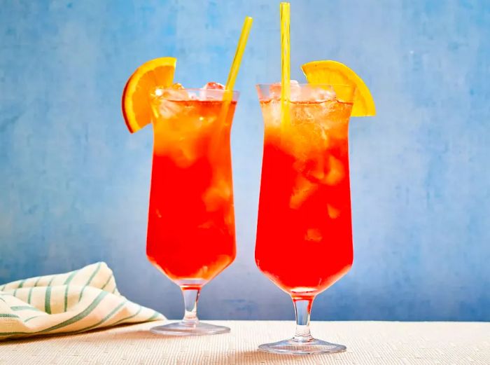 Two Real Rum Runner cocktails served over ice, each garnished with a fresh orange slice