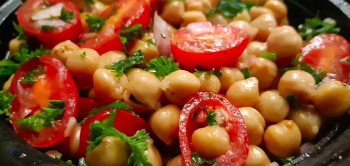 A close-up of a chickpea salad with tomatoes, parsley, and red onion