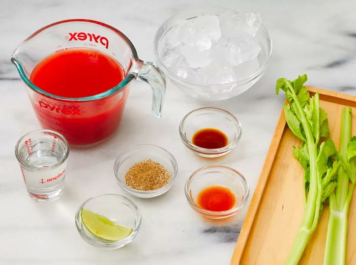 An overhead shot of the ingredients for a classic Canadian Caesar cocktail arranged on a kitchen countertop.