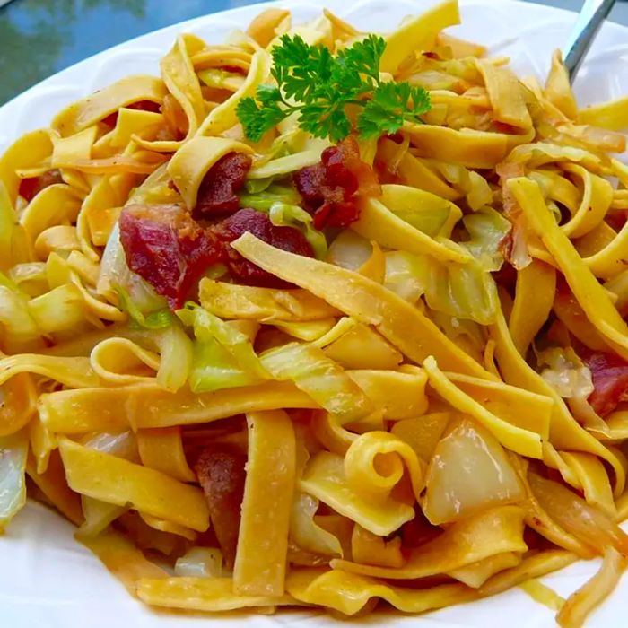 A close-up of Halushki garnished with fresh herbs on a white plate