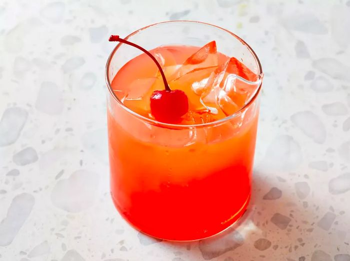 A high-angle view of a Pineapple Upside-Down Cake Cocktail topped with a maraschino cherry