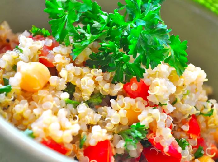 A close-up of Quinoa with Chickpeas and Tomatoes, topped with fresh herbs in a bowl