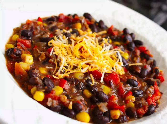 A close-up shot of Black Bean Chili topped with cheese in a white bowl