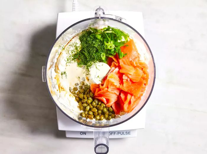 Bird's-eye view of all the salmon ingredients placed in a food processor, ready to be blended.