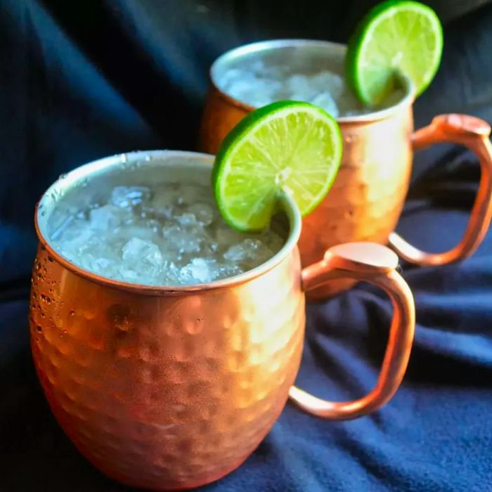 Moscow mule cocktails served in hammered copper mugs, garnished with lime