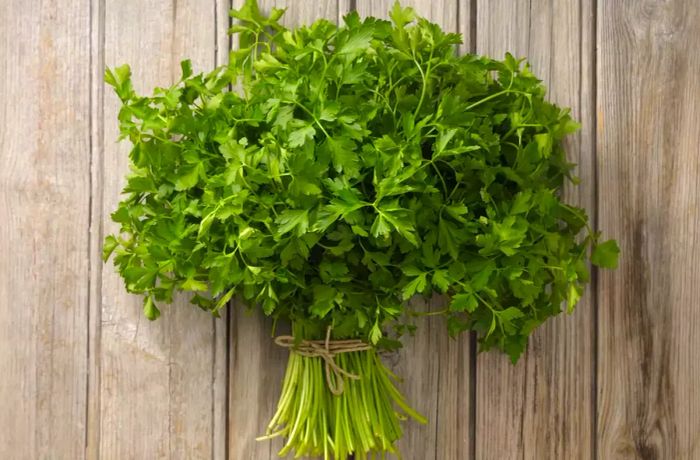 A fresh bunch of parsley resting on a wooden surface