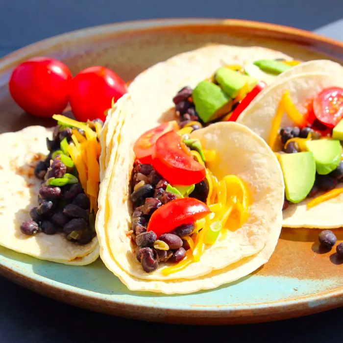 A close-up of Black Bean Tacos with tomatoes and avocado on a plate