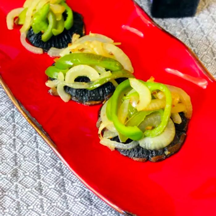 Three portobello mushroom caps topped with sautéed veggies, served on a red platter